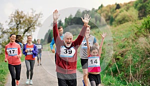 Large group of multi generation people running a race competition in nature.