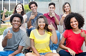 Large group of pretty international young adults showing thumb u