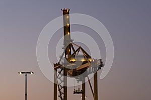 A large harbor crane against a vivid sky during the sunset
