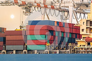 Large harbor cranes loading containers in the ships wiht sunset scene