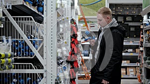 Large hardware store. Young man in a hardware store. A man in a hardware store chooses accessories for watering the lawn