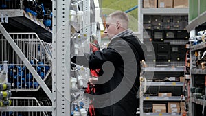 Large hardware store. Young man in a hardware store. A man in a hardware store chooses accessories for watering the lawn