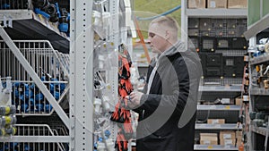 Large hardware store. Young man in a hardware store. A man in a hardware store chooses accessories for watering the lawn