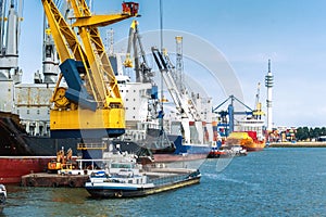 Large heavy-duty container ship with smaller boats in the port o