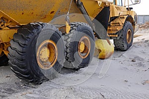 Large heavy duty tires on a large yellow construction vehicle on a sandy beach