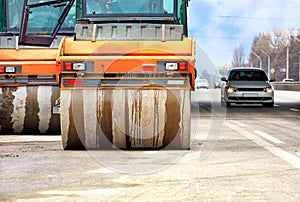 Large and heavy orange vibratory rollers move along the carriageway of the city road