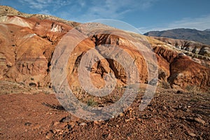 Large hills of red and yellow clay, traces of erosion, rocky surface and sparse vegetation