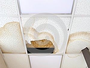 A large hole in the ceiling and stains from the water, due to damage to the roof during rain.