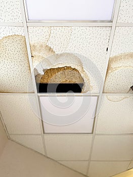 A large hole in the ceiling and stains from the water, due to damage to the roof during rain.