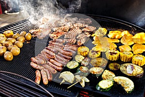 Large hot barbecue with meat, sausages and vegetables being cook