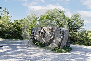 A large, huge stone megalith with a staircase against the background of green trees and a blue sky, used as an observation deck