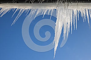 large icicles hanging from the roof on blue background