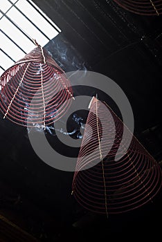 Large incense coils burning hanging from the ceiling of a Vietnamese Buddhist temple