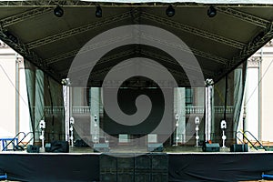 Large indoor outdoor stage for concerts. Professional sound and lighting equipment on stage. Monitor speakers and big screen on