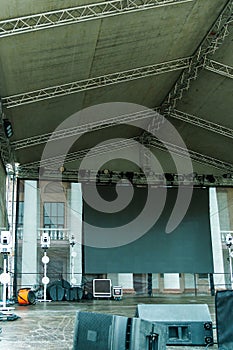 Large indoor outdoor stage for concerts. Professional sound and lighting equipment on stage. Monitor speakers and big screen on