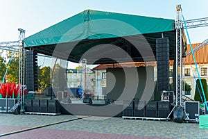 Large indoor outdoor stage for concerts. Professional sound and lighting equipment on stage. Monitor speakers and big screen on