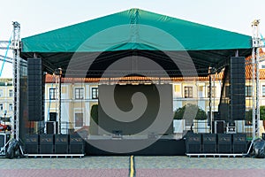 Large indoor outdoor stage for concerts. Professional sound and lighting equipment on stage. Monitor speakers and big screen on