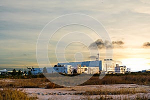Large industrial factory building in the middle of the field on beautiful golden or yellow and red sky at sunset of evening day