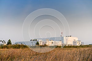 Large industrial factory building in the middle of the field on beautiful sunshine and blue sky at sunset of evening day
