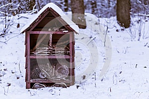 Large insect house covered in white snow, garden or forest decoration, winter season background