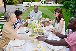 Large intercultural family of three generations holding by hands during pray