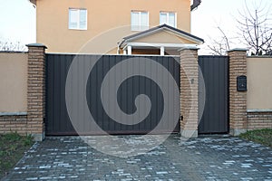 A large iron brown gate and a closed door with a part of a fence