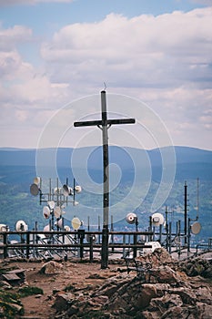 A large iron cross is contrasting with a telecommunication tower with multiple dish antennas. Czech Republic