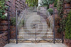 A large iron gate with a intricate design leading up to a house