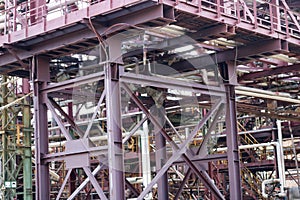 A large iron metal piping trestle with pipes and electric wires and equipment at the petrochemical refinery industrial refinery