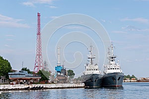 Large iron navy ships in shipyard for repair. Big crane in dockyard. Blue sea harbor. Ships anchorage