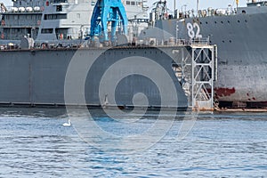 Large iron navy ships in shipyard for repair. Big crane in dockyard. Blue sea harbor