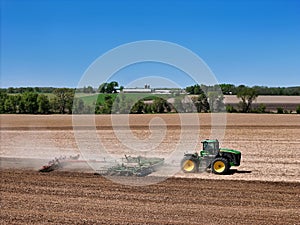 Large John Deere tractor pulling a John Deere disk cultivator