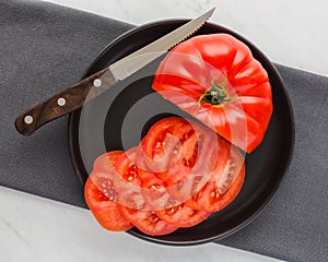 Large juicy red tomato part sliced on plate