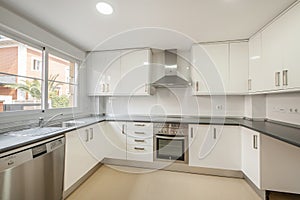Large kitchen with bright white cabinets, stainless steel appliances