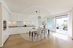 Large kitchen with dining table inside. Modern space and a window opening onto a terrace