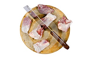 A large knife and pork sits on a wood chopping board isolated on