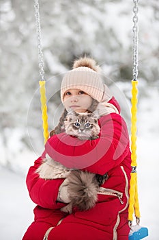 A large labrador dog and a cat in winter on a walk with a young woman in a snowy field