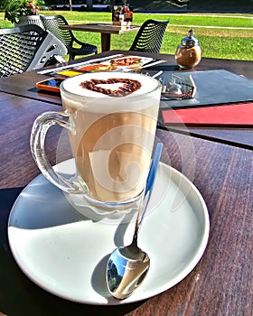 A large latte cup with a chocolate heart on the open veranda