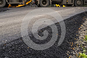 A large layer of fresh hot asphalt. Layer of asphalt raw material in a shallow depth of field. Rollers rollin fresh hot