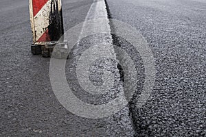 A large layer of fresh hot asphalt. Layer of asphalt raw material in a shallow depth of field. Rollers rollin fresh hot