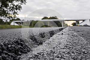 A large layer of fresh hot asphalt. Layer of asphalt raw material in a shallow depth of field. Rollers rollin fresh hot