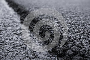 A large layer of fresh hot asphalt. Layer of asphalt raw material in a shallow depth of field. Rollers rollin fresh hot