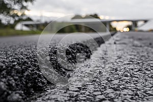 A large layer of fresh hot asphalt. Layer of asphalt raw material in a shallow depth of field. Rollers rollin fresh hot