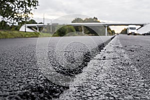 A large layer of fresh hot asphalt. Layer of asphalt raw material in a shallow depth of field. Rollers rollin fresh hot