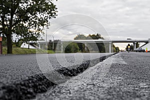 A large layer of fresh hot asphalt. Layer of asphalt raw material in a shallow depth of field. Rollers rollin fresh hot