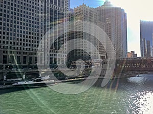 A large leisure boat docked on riverwalk of Chicago River with recreation & leisure seekers covered by colorful sunbeams in Chicag