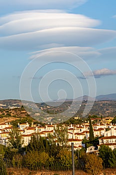 Large lenticular clouds over the roofs of residential houses in a housing estate