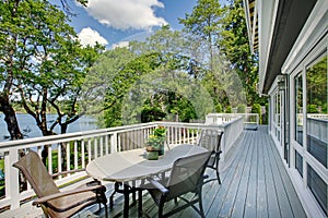 Large long balcony home exterior with table and chairs, lake view. photo