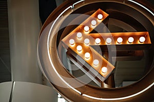 large luminous arrow decorated with light bulbs in the background of the airport interior