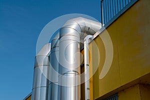 large luminous steel tubes, alongside a technical building, ventilation system pipes in the building.